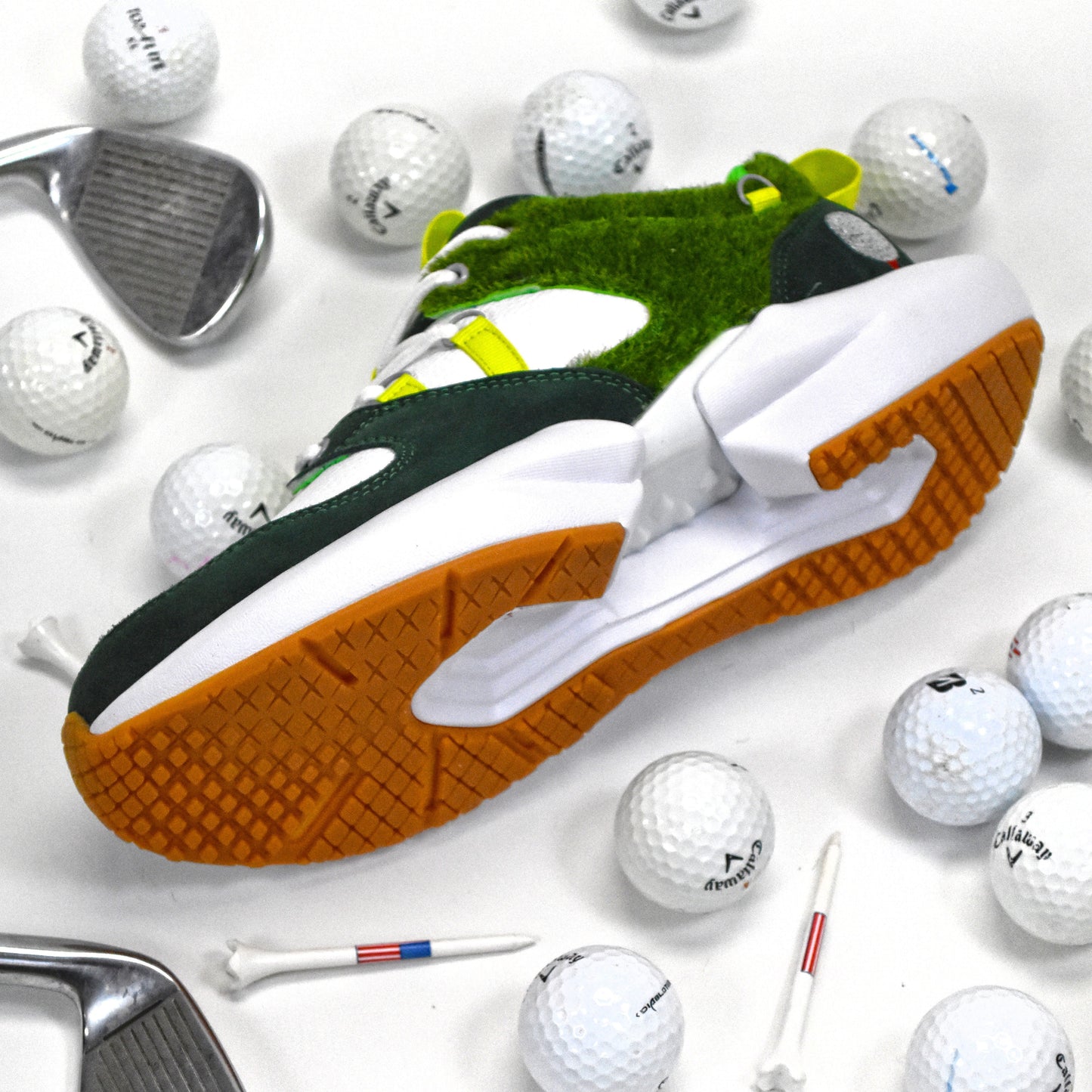 Golf shoes with green and white accents surrounded by golf balls and clubs on a white background